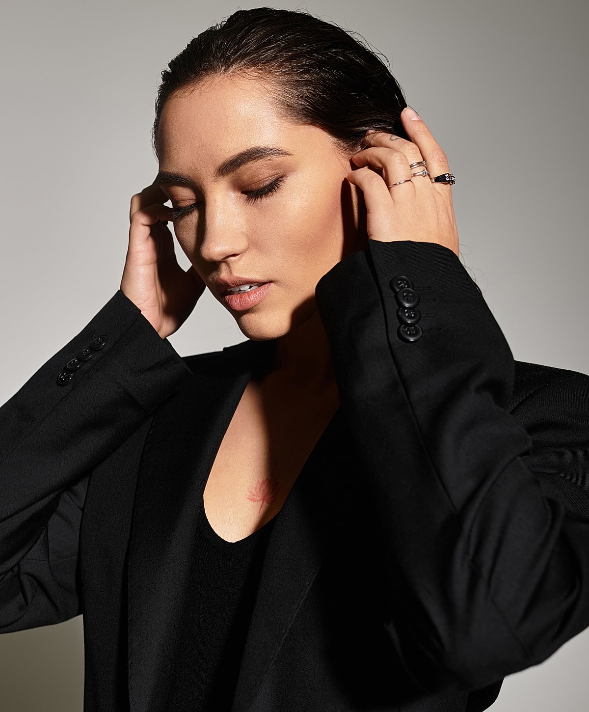 Woman in black suit with closed eyes, serene expression.