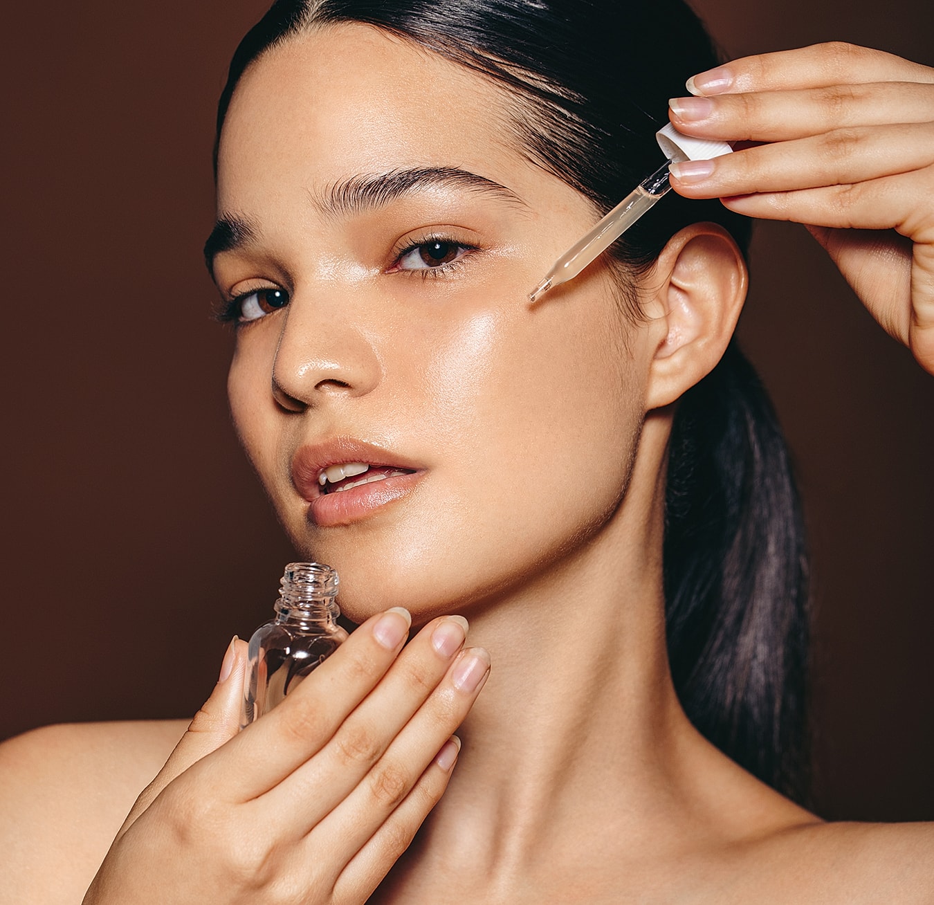 Woman applying facial serum with dropper.
